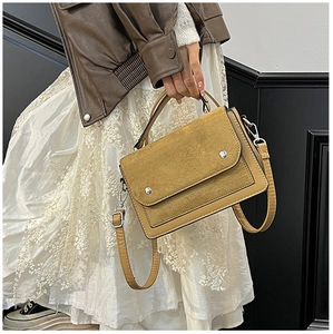 Detail of color-block yellow handbag with suede flap and metallic ring hardware