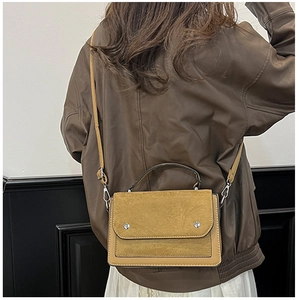 Detail of color-block crossbody bag featuring mixed textures and silver metallic studs
