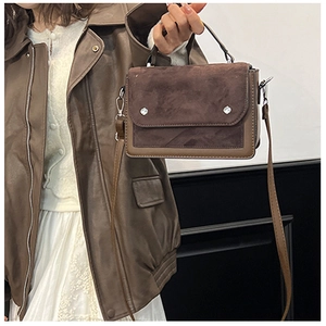 Detail of color-block coffee leather handbag with suede texture and metal studs