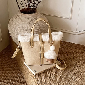 Faux shearling bucket bag in beige suede with furry pompom and adjustable strap
