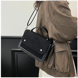 Detail view of the contrast-texture flap with silver rivets on this black crossbody bag