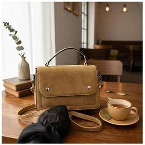 Detail of khaki color-block handbag with matte finish and silver rivets in cafe setting