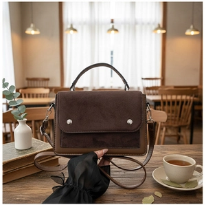 Detail of color-block tote bag with silver buckles in a cozy cafe setting