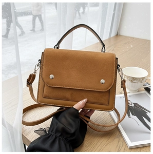 Detail of contrast stitch handbag featuring brown suede patchwork and silver studs on table