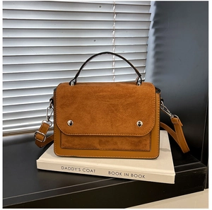 Detail of two-tone brown crossbody bag with suede flap and silver metallic hardware