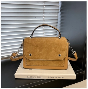 Detailed shot of contrast stitching and silver circular buckle on crossbody bag