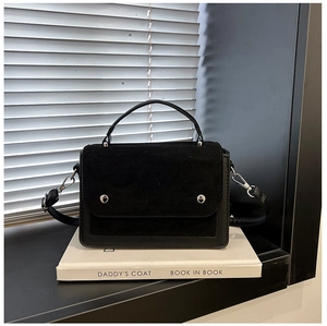 Detail of black contrast texture handbag with matte flap and silver studs on white background