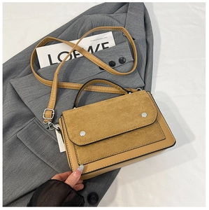 Detail view of mustard yellow patchwork handbag with suede flap and silver studs