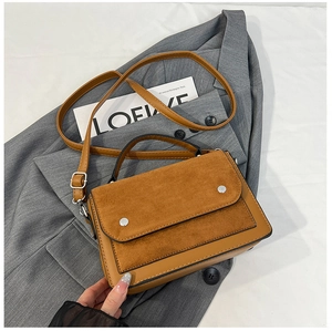 Detailed view of color-block flap bag on grey blazer with dual-material leather texture