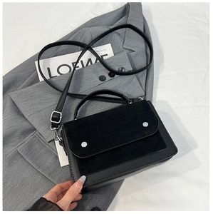 Detail of color-block crossbody bag featuring mixed textures and silver stud accents
