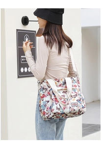 Dettaglio della borsa tote in nylon con motivi a farfalla colorati e tracolla bianca