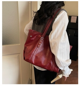 Macro shot of dark red vintage leather tote bag featuring contrast stitching and rivets