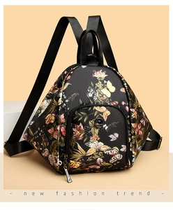Detail of black backpack with floral butterfly patterns and metallic logo ornament