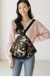 Detailed view of black floral backpack featuring colorful butterfly patterns and front pocket