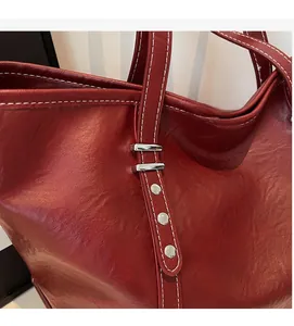 Detail of dark red leather tote bag with white contrast stitching and silver hardware