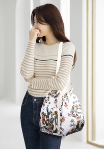 Side view of white butterfly floral print backpack worn by a model in a bright room