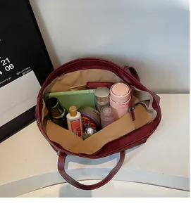 Detailed view of dark red tote bag interior featuring spacious storage and zip pocket