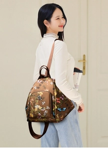 Brown nylon backpack with colorful butterfly print and adjustable woven straps on model