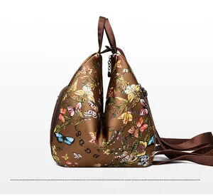 Detail view of the brown backpack side zipper and vibrant floral butterfly print