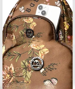 Detail of floral brown backpack featuring durable front zipper pocket and gold logo hardware
