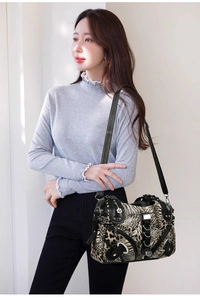 Detail of leopard print leather bag with silver metal rings and floral charm