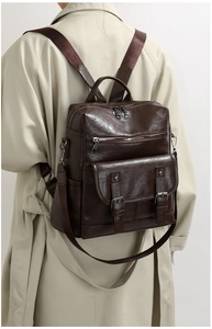 Detail of dark brown vintage faux leather backpack with multiple pockets on model