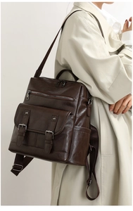 On-body view of a vintage dark brown leather backpack with multiple pockets and straps