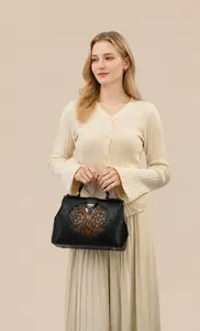 Close-up of vintage black handbag with embossed floral pattern and metal buckle detail