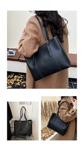 Detail of a large vintage black tote bag with white stitching shown in outdoor autumn setting