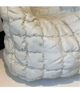 Détail de la texture matelassée blanche et des surpiqûres carrées du sac à main