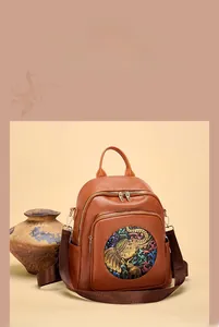 Detail of vintage brown leather backpack featuring a colorful elephant patch and zippers