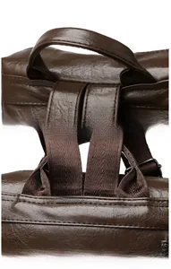 Close-up of the reinforced stitching and leather handle on the vintage brown backpack