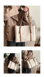 Detailed view of large cream tote bag with dark brown handles and gold hardware accents
