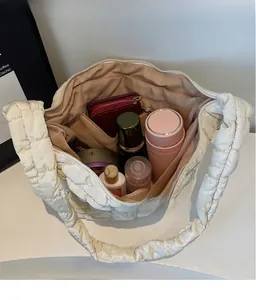 Vue de dessus montrant la grande capacité d'un sac matelassé blanc avec des objets