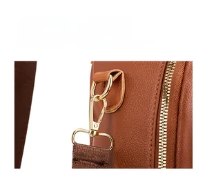 Close-up of golden hardware and brown litchi grain leather on this travel backpack