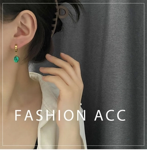 Détail de la boucle d'oreille goutte émeraude avec cerceau doré porté par un mannequin