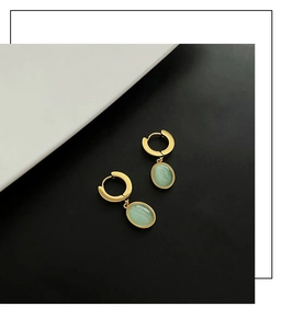 Détail macro de boucles d'oreilles créoles dorées avec zircons vert émeraude en goutte