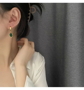 Détail de boucles d'oreilles créoles avec pendentif en zircon vert émeraude sur un mannequin