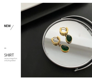 Détail des pierres précieuses vert émeraude sur créoles dorées avec reflet de miroir