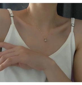 Gros plan d'un collier pendentif lapin doré avec zircons brillants sur un cou féminin