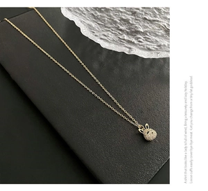 Vue détaillée du pendentif lapin doré avec cristaux pavés sur un support texturé