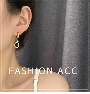 Détail de boucles d'oreilles dorées avec chiffres romains, insert noir et pierre zircon