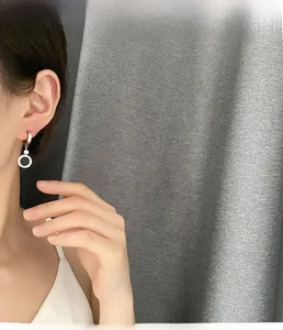Boucles d'oreilles créoles argentées avec zircon noir portées sur l'oreille du mannequin