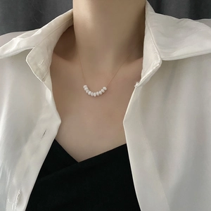 Elegant gold choker necklace with nine white pearls in a minimalist smile curve design