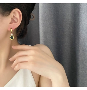 Détail de la boucle d'oreille dorée en titane avec pendentif noir et pierre zircone