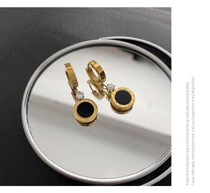 Détail de boucles d'oreilles romaines dorées avec zircon noir et reflet sur miroir