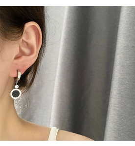Détail des boucles d'oreilles créoles en acier avec chiffres romains et pierres noires
