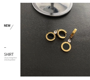 Détail de boucles d'oreilles dorées avec pendentifs chiffres romains noirs et zircon