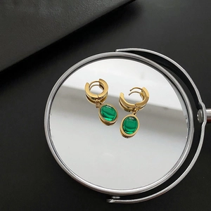 Élégantes boucles d'oreilles goutte en zircon vert émeraude dorées sur un miroir