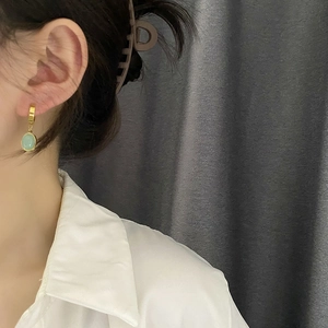 Élégantes boucles d'oreilles dorées avec zircon vert émeraude portées par un mannequin